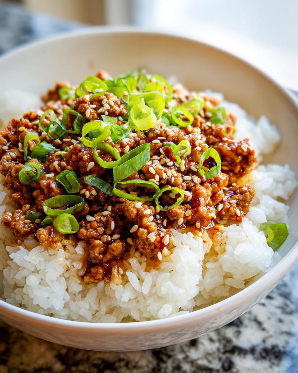 Close-up of a Teriyaki Turkey Rice Bowl featuring ground turkey in teriyaki sauce over white rice, topped with green onions and sesame seeds.