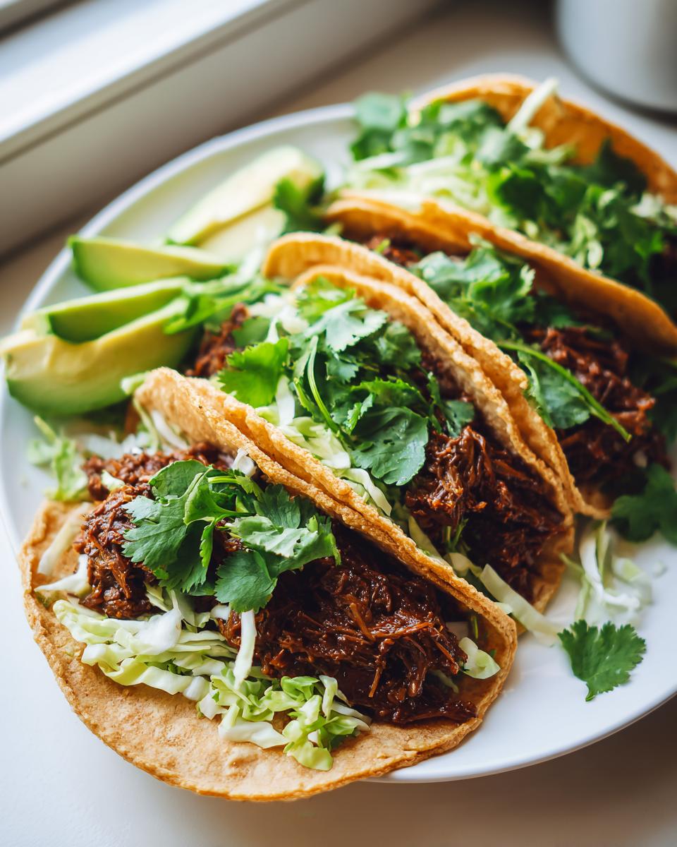 Three fully loaded Vegan Jamaican Jerk Walnut Tacos served on a white plate with sliced avocado.