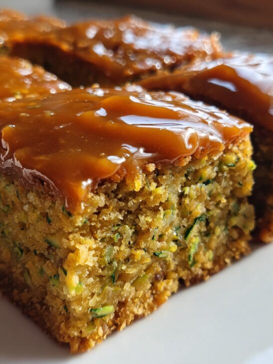 Close-up of moist Zucchini Bars With Caramel Frosting cut into squares and served on a white plate.