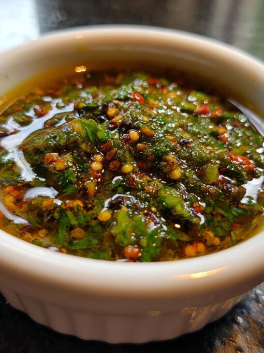 A small white ramekin filled with vibrant green, oily 5 Minute Zesty Chili Lime Marinade, flecked with red chili flakes.