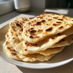 A stack of freshly cooked, slightly charred flatbreads, representing The Only Bread Which You Can Eat As Much As You Like.