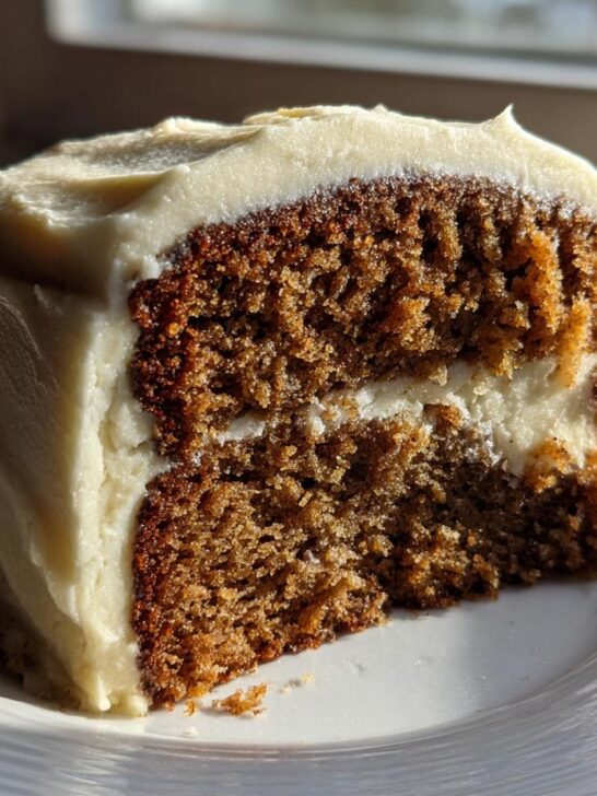 A moist slice of Banana Bread Cake With Cream Cheese Frosting layered with thick cream cheese frosting.