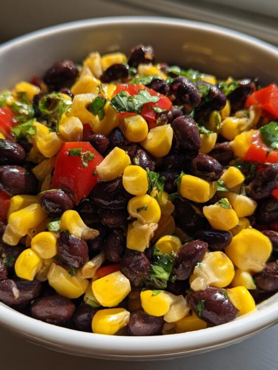 Close-up of a white bowl filled with colorful Black Bean Corn Salsa featuring black beans, yellow corn, and red tomatoes.