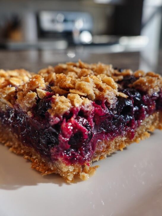 A close-up of one square Blueberry Oatmeal Bars slice showing a thick, jammy blueberry filling and crumbly oat topping.