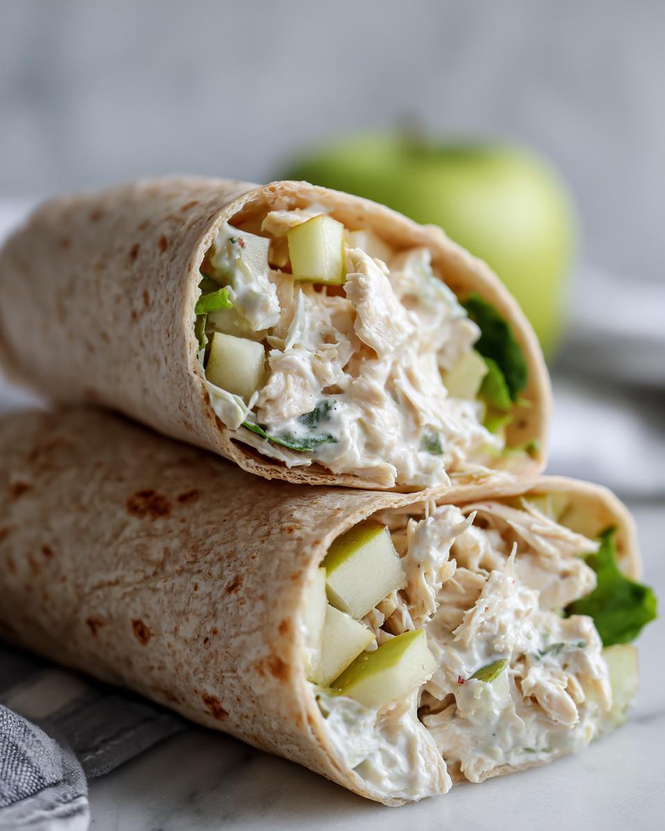 Two halves of Chicken Apple Salad Wraps stacked, showing shredded chicken salad mixed with diced green apples.