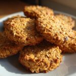 A stack of golden brown, textured Chickpea Seed Crackers loaded with visible seeds on a light gray plate.
