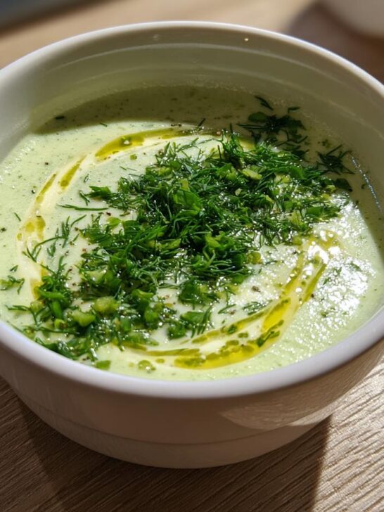 Close-up of a bowl of Cold Cucumber Soup With Yogurt And Dill, garnished with fresh dill and olive oil.