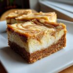 A thick, square slice of Dulce De Leche Cheesecake Bars showing a graham cracker crust, creamy filling, and swirled topping.