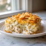 A close-up serving of Green Chile Chicken And Rice Casserole with melted cheese and crunchy tortilla chip topping.