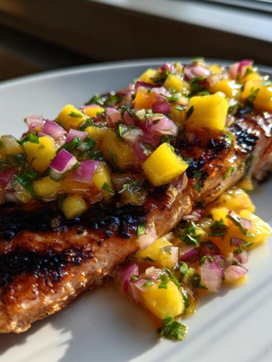 A perfectly grilled salmon fillet topped generously with vibrant mango salsa, showcasing the recipe for Grilled Salmon With Mango Salsa.