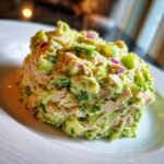 A mound of creamy Healthy Avocado Tuna Salad mixed with chunks of avocado, tuna, and red onion on a white plate.