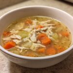 Close-up of a bowl of shredded chicken soup with carrots and celery, a perfect example of high protein low carb soups.