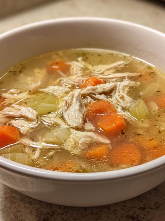 Close-up of a bowl of shredded chicken soup with carrots and celery, a perfect example of high protein low carb soups.