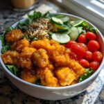 A close-up of a Hot Honey Chicken Bowl Sweet Green Copycat featuring glazed chicken pieces, quinoa, cherry tomatoes, and cucumbers.