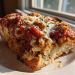 A thick, baked slice of My Italian Grandmothers Eggplant Recipe topped with red sauce and melted cheese.