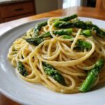 A close-up shot of creamy Lemon Asparagus Pasta tossed with bright green asparagus spears on a white plate.