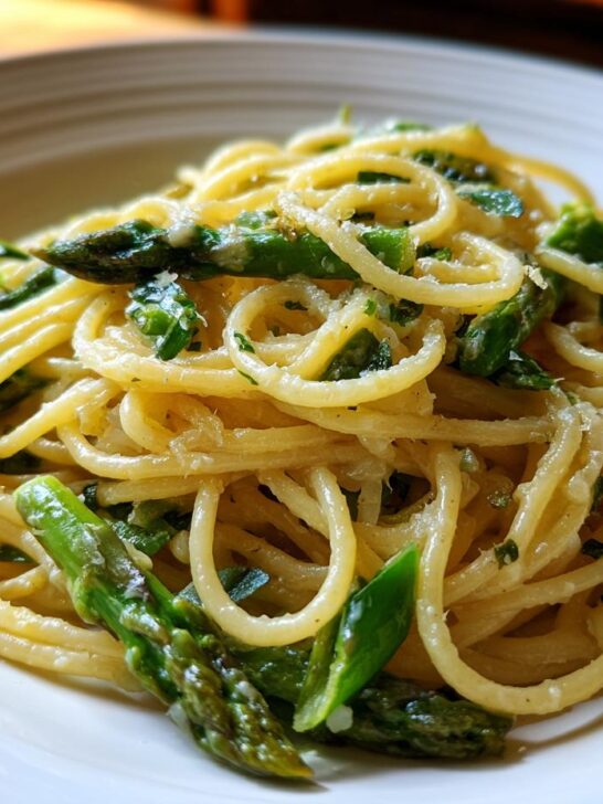 A close-up shot of bright Lemon Asparagus Pasta tossed with bright green asparagus pieces and grated cheese.