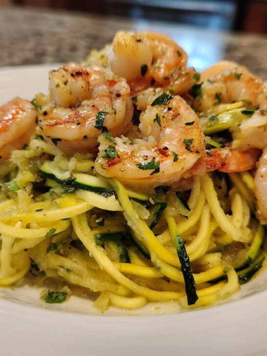 A close-up of perfectly cooked Lemon Garlic Shrimp And Zucchini Noodles served on a white bowl.