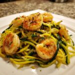 Close-up of Lemon Garlic Shrimp And Zucchini Noodles, featuring seared shrimp atop yellow and green zucchini spirals.