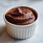 Close-up of rich, dark chocolate cottage cheese mousse served in a small white fluted ramekin.