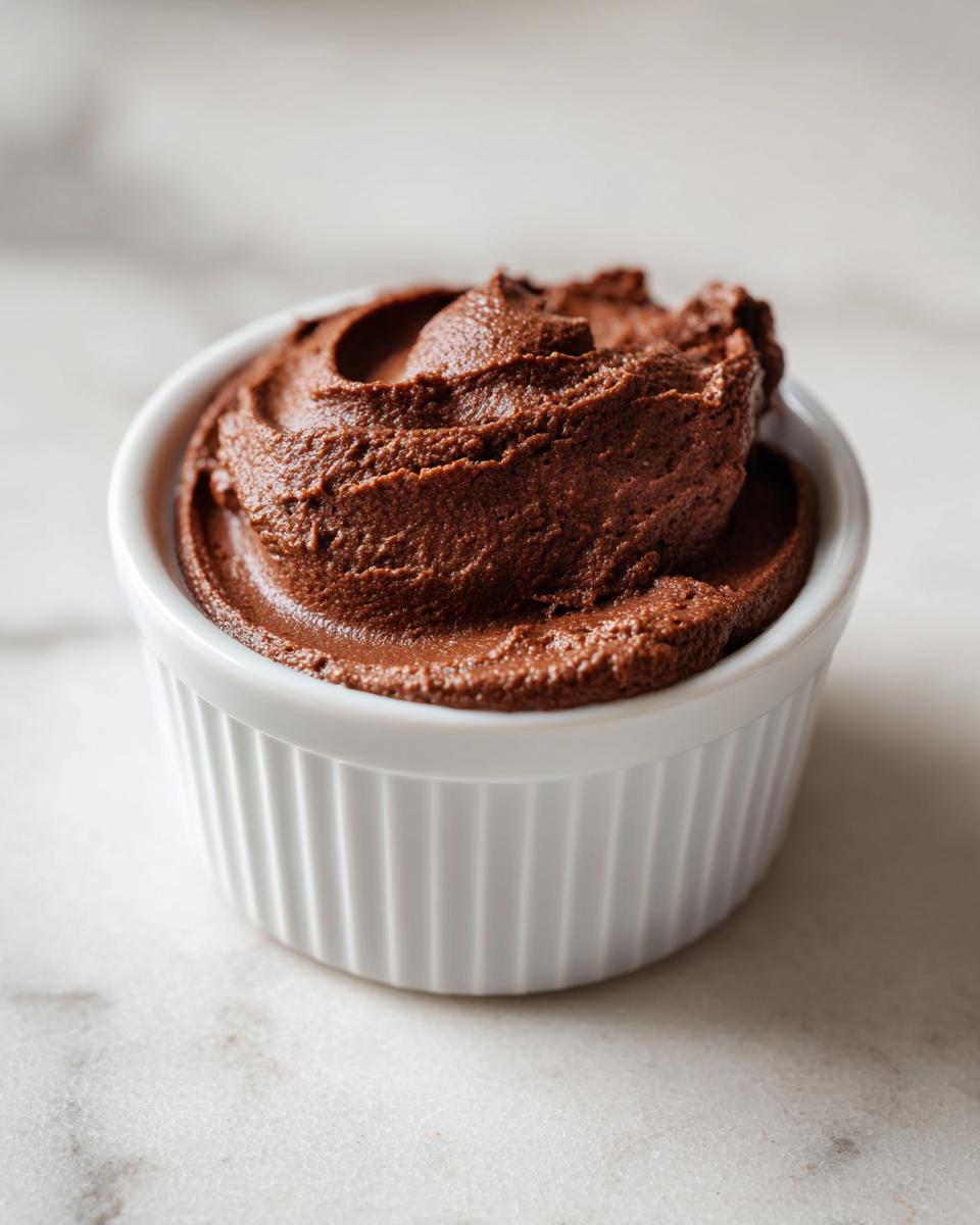A close-up of rich, dark chocolate cottage cheese mousse served in a white fluted ramekin.