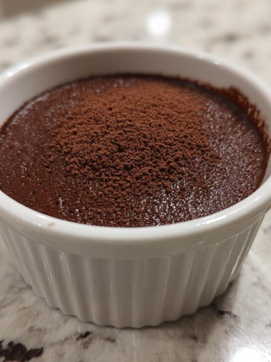 A single serving of rich, dark Low Carb Chocolate Cottage Cheese Mousse topped with cocoa powder in a white ramekin.