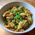 A close-up of a serving of Low Carb Egg Roll In A Bowl with ground meat, cabbage, and green onions.