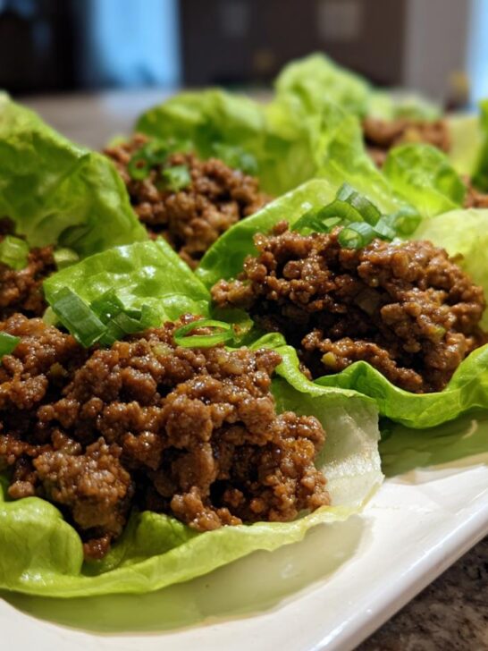 Several servings of Mexican ground beef lettuce wraps filled with seasoned ground beef and topped with green onions.