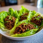 Four servings of Mexican Ground Beef Lettuce Wraps filled with seasoned ground beef and topped with cilantro.