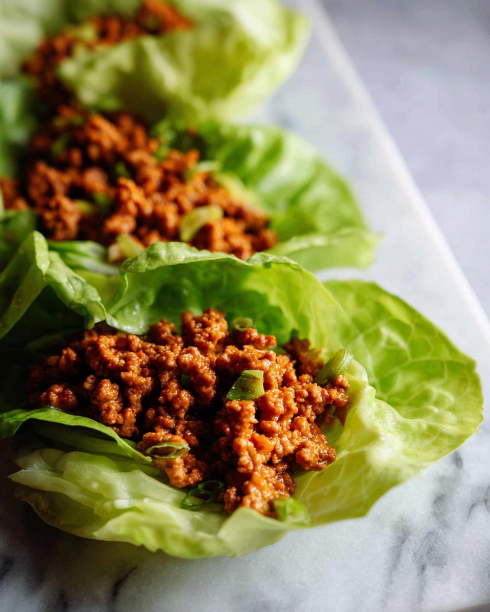 Close-up of seasoned Mexican ground beef mixture served in crisp lettuce cups, ready to eat.