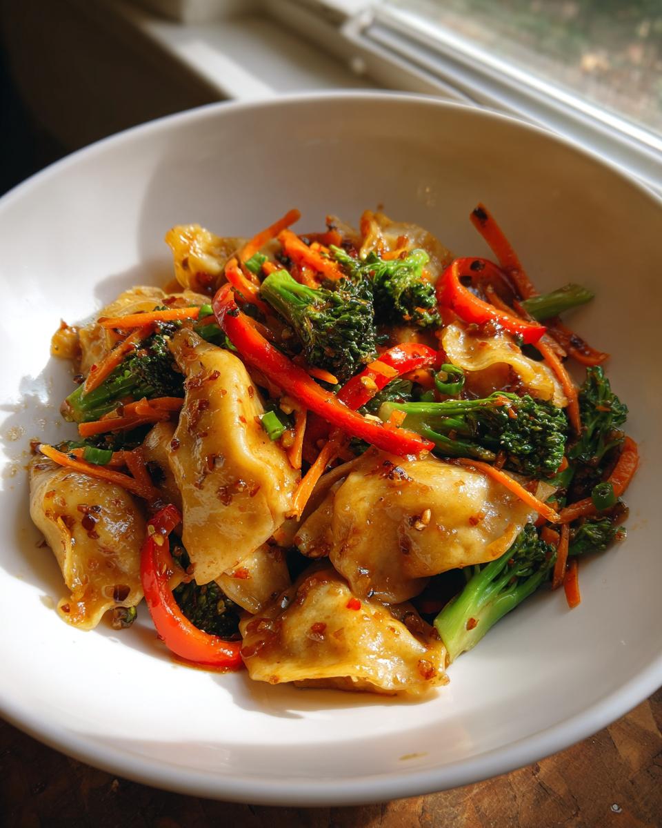 Close-up of a white bowl filled with Potsticker Stir Fry featuring dumplings, bright green broccoli, red peppers, and carrots.
