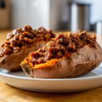 Two baked sweet potatoes split open and generously filled with savory Sloppy Joe Sweet Potato Bowls topping.