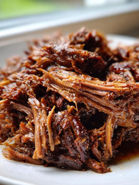 Close-up of tender, shredded Slow Cooker Beef Barbacoa piled on a white plate.