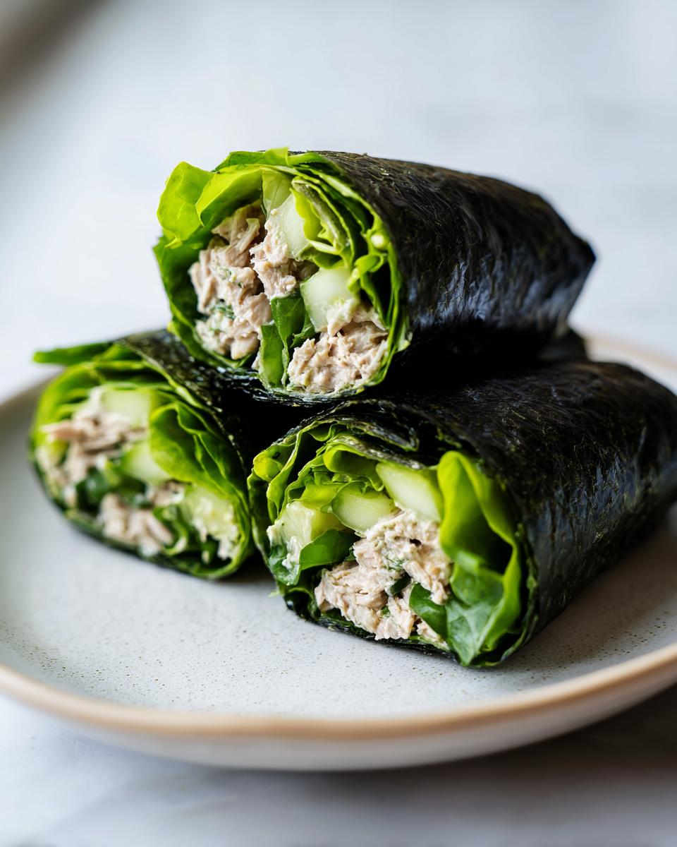 Three cross-section views of Tuna Salad Nori Wraps filled with tuna salad, lettuce, and cucumber, stacked on a plate.