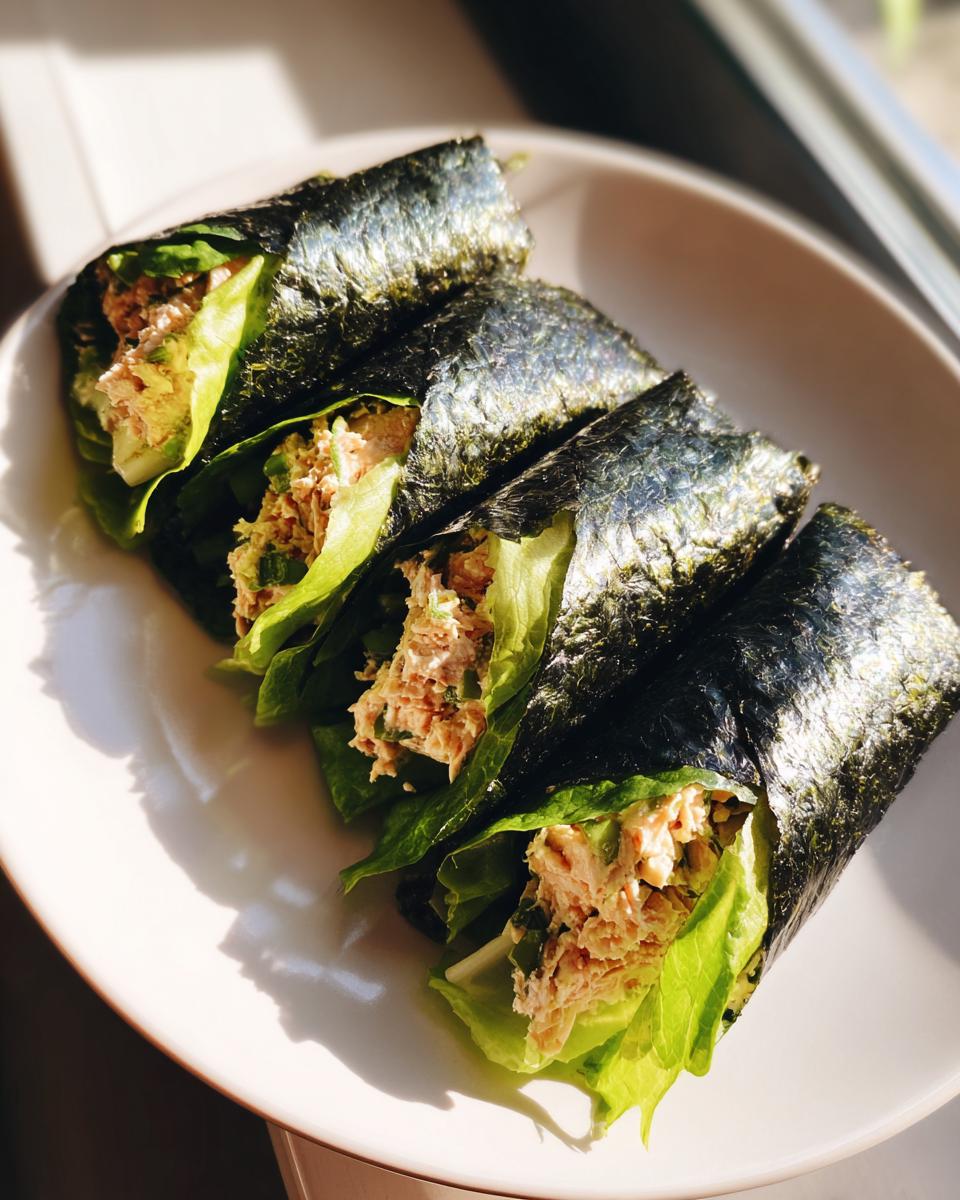 Four fresh Tuna Salad Nori Wraps arranged on a white plate, filled with tuna mixture, lettuce, and wrapped in dark seaweed.