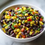 Close-up of vibrant Black Bean Corn Salsa featuring black beans, yellow corn, red peppers, and cilantro in a white bowl.