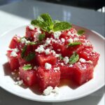 Close-up of vibrant Watermelon Feta Salad With Mint, featuring cubed watermelon topped with crumbled feta and fresh mint leaves.